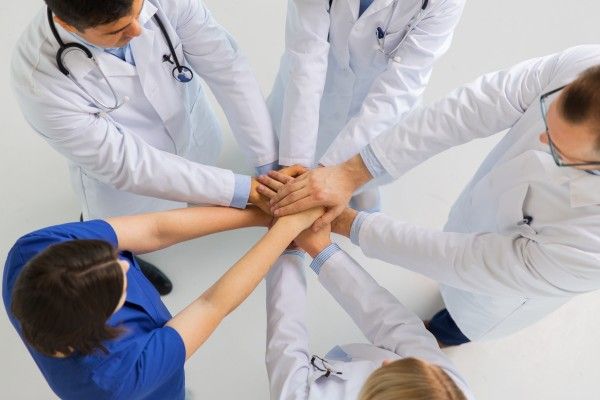 group of doctors with hands together at hospital